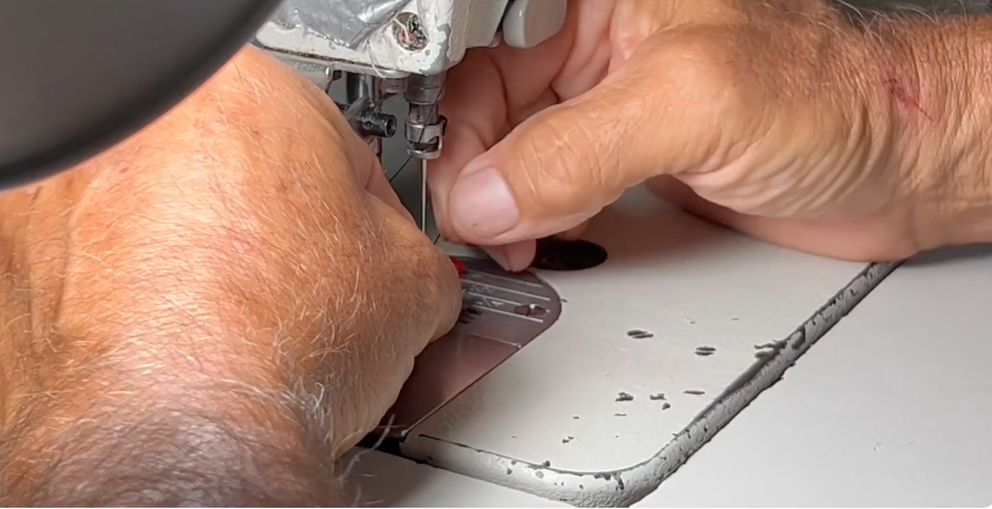 Close-up of a tailor’s hands guiding fabric near the sewing machine needle at Doxa Couture in Downey, California.