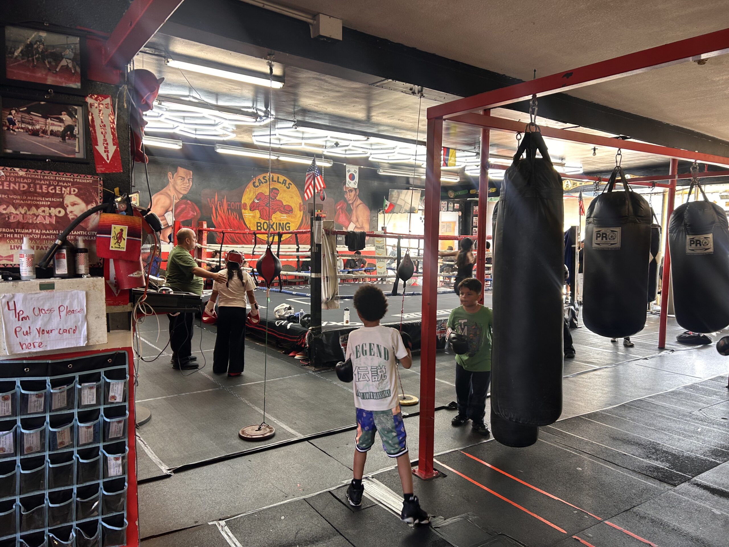 youth boxing training at Casillas Boxing Gym in Linwood California with kids practicing on heavy bags and boxing ring in background