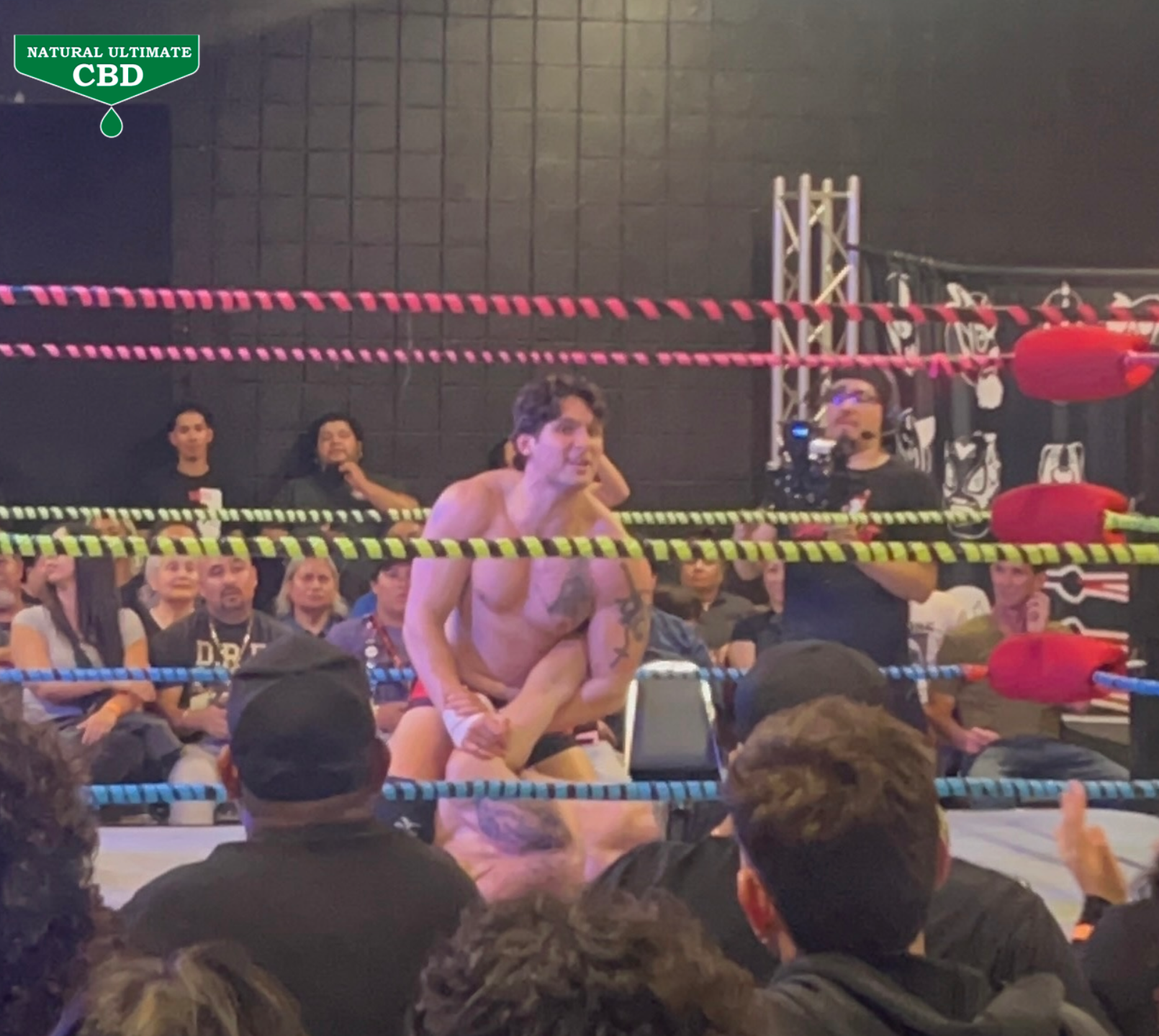 Wrestler applying leg hold during Santino Bros Wrestling match in Azusa California with crowd watching ringside