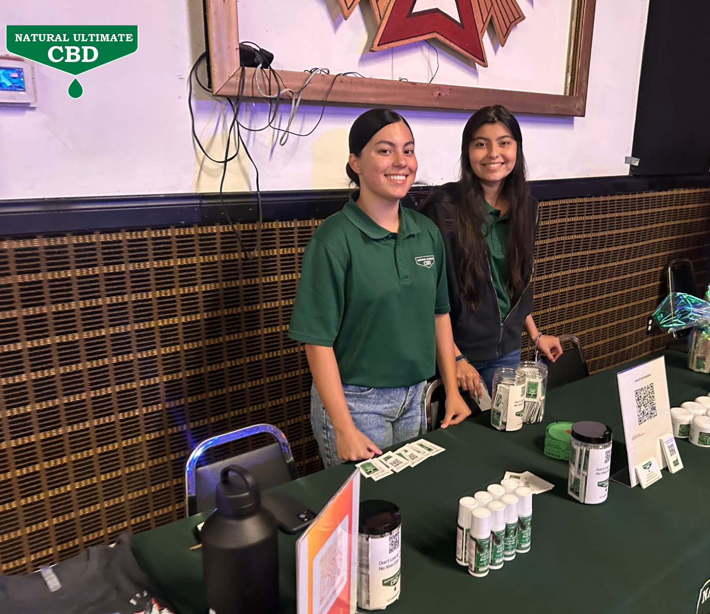 Natural Ultimate CBD vendor booth with staff and topical CBD products at Santino Bros Wrestling event in Azusa California